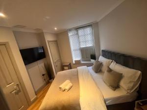 1 dormitorio con 1 cama grande con sábanas y almohadas blancas en Central private 1 bed flat, en Reading