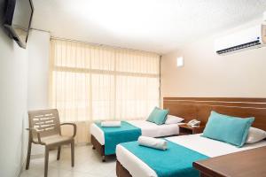 a hotel room with two beds and a chair at Hotel Portobelo Convention Center in San Andrés