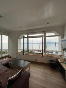 - un salon avec un canapé et quelques fenêtres dans l'établissement Charmant studio - Vue panoramique lac, à Meillerie