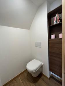 La salle de bains est pourvue de toilettes blanches et d'une étagère en bois. dans l'établissement Charmant studio - Vue panoramique lac, à Meillerie