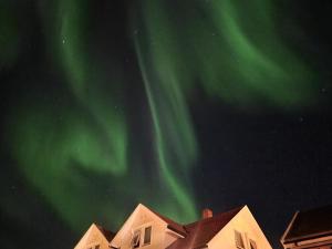 una imagen de la aurora en el cielo sobre las casas en Cosy nordic apartment, en Tromsø