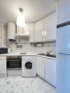 a white kitchen with a washing machine and a sink at Lovely studio con balconcitos in Madrid