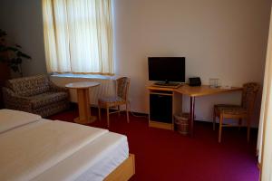 a hotel room with a bed and a table and a television at Hainberg Hotel Garni in Habrachćicy