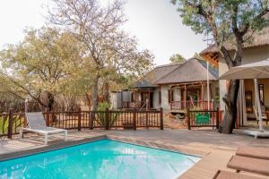 a house with a swimming pool in front of a house at Zebula Lodge 118 in Mabula