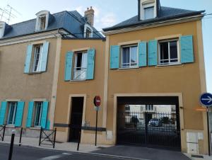 um edifício com janelas azuis e uma garagem em Studio Cosy en centre ville em Arpajon