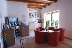 a living room with chairs and a table and a television at Füzesi Papa Vendégháza in Harta