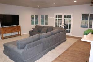 a living room with a large couch and a flat screen tv at 1940 Farmhouse with Pool in Newcastle