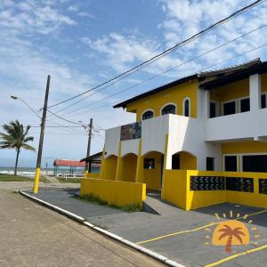 a yellow and white building next to the ocean at Suítes Temporada Favorita in Peruíbe