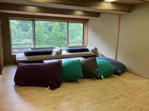 Oshuku Onsen Choeikan - Vacation STAY 55599v في Shizukuishi: غرفة بها العديد من الوسائد على الأرض أمام النافذة