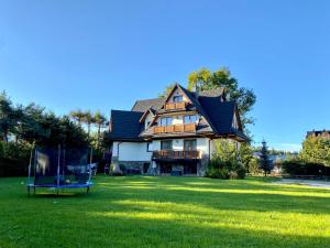 une grande maison avec une cour et une balançoire dans l'établissement Pod Lipą 2, à Białka Tatrzańska