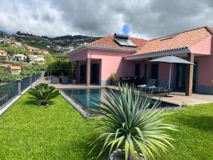 een roze huis met een zwembad in een tuin bij Villa Livramento in Ponta do Sol