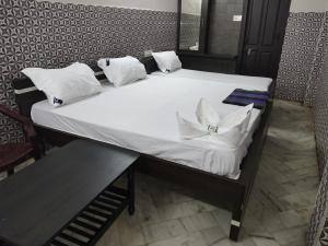 a bed with white sheets and pillows on it at Hotel Karthikeya Residency in Kākināda