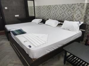 2 letti con lenzuola bianche e asciugamani di Hotel Karthikeya Residency a Kākināda