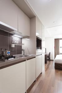- une cuisine avec des placards blancs et un lit dans une chambre dans l'établissement Urban Place Gangnam, à Séoul