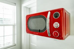 a red microwave hanging on a wall next to a window at 13 The Eero Room - A PMI Scenic City Vacation Rental in Chattanooga