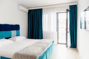 een slaapkamer met een bed, blauwe gordijnen en een raam bij The blue Norwegian house in Boekarest