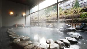 Cette chambre dispose d'une piscine d'eau avec des rochers. dans l'établissement Oshuku Onsen Choeikan - Vacation STAY 55578v, à Shizukuishi