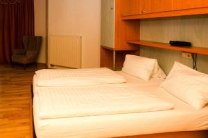 2 weiße Betten in einem Zimmer mit Stuhl in der Unterkunft Apartment in Podersdorf am See with a bicycle storage in Podersdorf am See