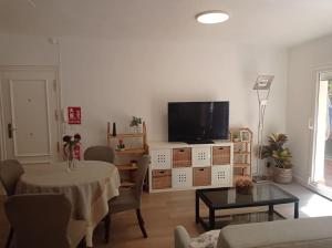 a living room with a table and a television on a cabinet at Piso con terraza junto a la playa in San Sebastián