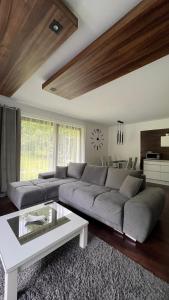 a living room with a large couch and a table at Dom - Apartamenty Prestige - opcja jacuzzi i sauna in Solina