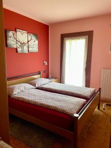 a bedroom with a bed with red walls and a window at Casa Federica in Valdidentro