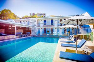 uma piscina com cadeiras e um guarda-sol e um edifício em Rambutan Resort em Townsville