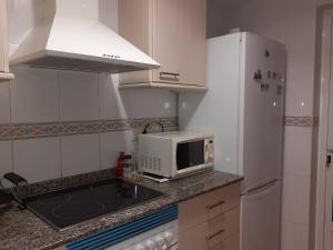 a small kitchen with a sink and a microwave at Amanecer marino, solo a 5 minutos andando de la playa in Puzol