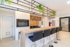 una cocina con una barra larga con sillas negras en CWBe Residencial, en Curitiba