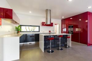 uma cozinha com armários vermelhos e um balcão com bancos em Casa Genne em Torres Vedras