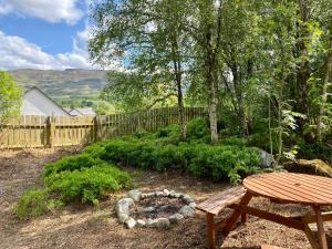 a garden with a wooden table and a wooden fence at Homestead Cottage, Fort Augustus in Fort Augustus