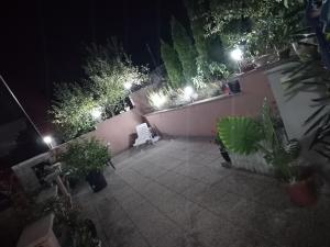 a patio at night with a white bench and plants at Apartment AMRA in Tuzla