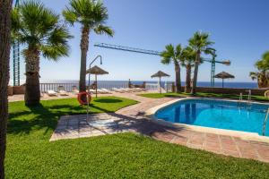 a pool with palm trees and the ocean in the background at RentitSpain - Almuñecar - Vistas Increíbles al mar en Apartamentos Lambda in Almuñécar