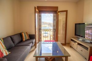 a living room with a couch and a tv at RentitSpain - Almuñecar - Vistas Increíbles al mar en Apartamentos Lambda in Almuñécar