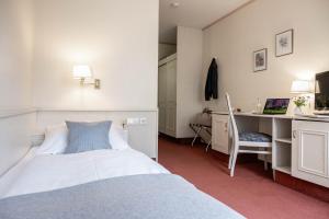 a bedroom with a bed and a desk with a computer at Hotel Ilmenautal inklusive THERMEplus in Bad Bevensen