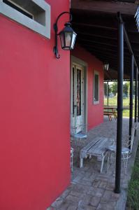 a red wall with a picnic table and a bench at Pasos de la Naturaleza in San Andrés de Giles