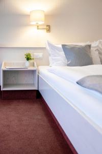 a bedroom with a large white bed with a side table at Hotel Ilmenautal inklusive THERMEplus in Bad Bevensen
