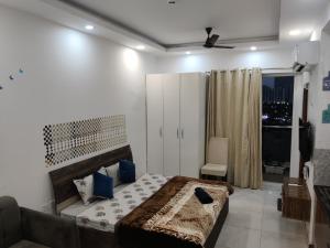 a bedroom with a bed with blue pillows and a window at The Forest Stays-Luxury Studio Apartment In Noida in Noida