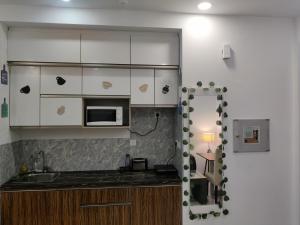 a kitchen with white cabinets and a counter top at The Forest Stays-Luxury Studio Apartment In Noida in Noida