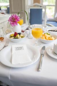 einen Tisch mit Teller mit Lebensmitteln und ein Glas Orangensaft in der Unterkunft Hotel Ilmenautal inklusive THERMEplus in Bad Bevensen