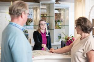 a woman standing at a counter talking to two people at Hotel Ilmenautal inklusive THERMEplus in Bad Bevensen