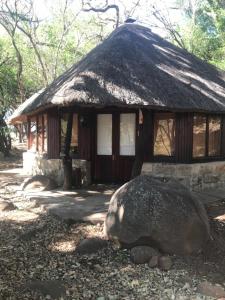 una pequeña cabaña con una gran roca delante de ella en Kameelkop Nature Reserve Lodge & Chalets, en Wasbank