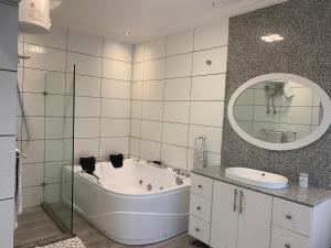 ein Badezimmer mit einer Badewanne, einem Waschbecken und einem Spiegel in der Unterkunft After 5 Apartment 3 2 spacious en-suite bedrooms in Freetown