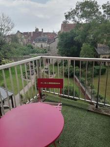 a pink table and a red chair on a balcony at Le Tivoli - Balcon Vue jardin in Dijon