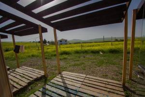 a wooden bench under awning in a field of grass at Oasis Club Cottages in Udabno