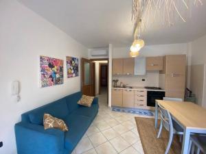 uma sala de estar com um sofá azul e uma cozinha em Residenza Brancadoria em Valledoria