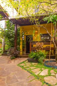 a garden with a yellow house with a bench at AquariusApart in Morro de São Paulo