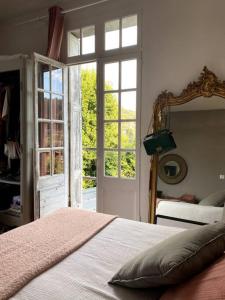 a bedroom with a bed and a mirror and a window at La Villa Lumaga in Étretat