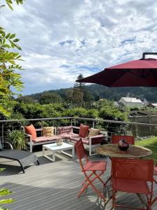 eine Terrasse mit Stühlen, einem Tisch und einem Sonnenschirm in der Unterkunft La Villa Lumaga in Étretat