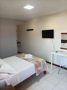 a bedroom with a bed and a desk and a television at Pousada A Pérola in Rio de Contas