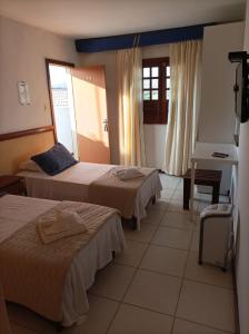 Cette chambre comprend deux lits et un bureau. dans l'établissement Pousada A Pérola, à Rio de Contas